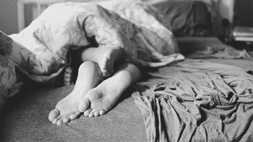 Couple plays footsy while cuddling in bed gif