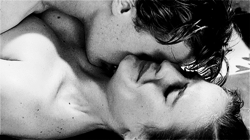 Man kisses woman's neck while cuddling in bed gif