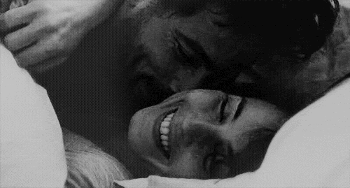 Playful Couple Laughing In Bed GIF
