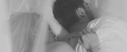 Woman rubs man's back while cuddling gif