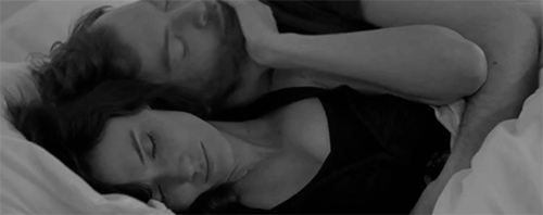 Woman rubs man's face while cuddling gif